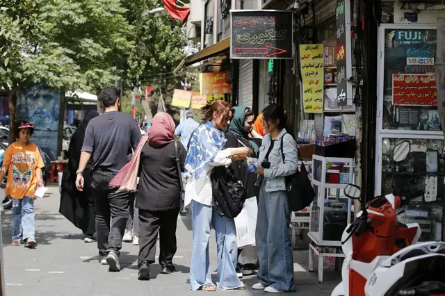 مردم در خیابانی در تهران در جریان جنگ اسرائیل و ایران