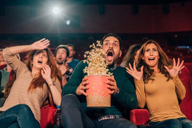 Penonton berteriak dan ketakutan saat menonton film horor di bioskop.