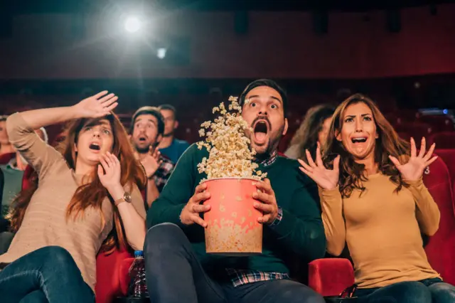 Penonton berteriak dan ketakutan saat menonton film horor di bioskop.