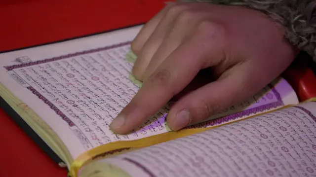 دست دختری روی صفحهای از یک کتاب دینی