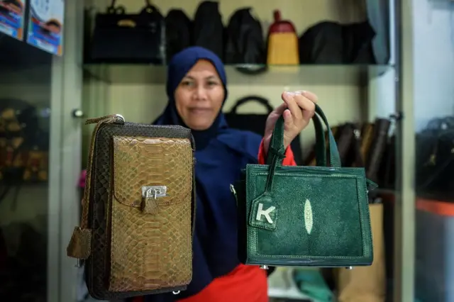 Seorang perempuan menunjukkan tas.