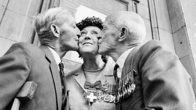 El sargento R. Ryder y el teniente coronel T. E. Adlam le dan un beso en cada mejilla a Odette en una convención de héroes de guerra condecorados con la Medalla George o la Cruz Victoria.