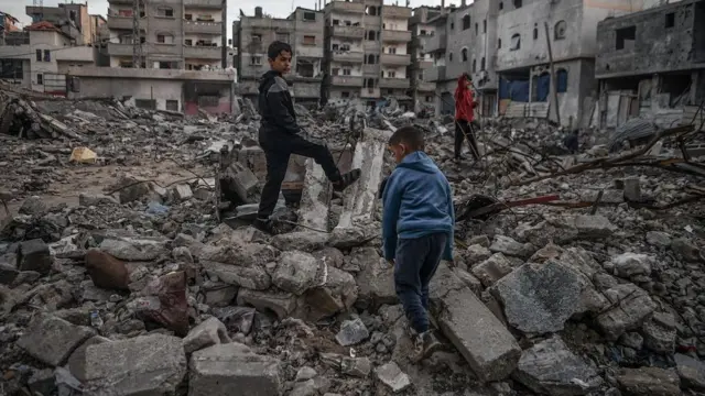 Palestinian boys are seen in the rubble of a building destroyed by an Israeli attack in Rafah, Gaza on 3 January 2024