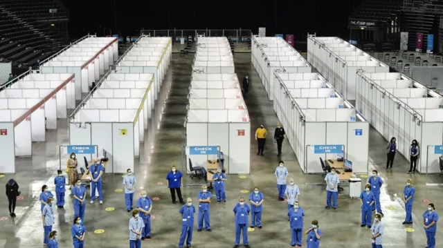 یک سالن برای واکسن زدن و تعدادی از کارکنان که فاصله اجتماعی را رعایت کرده‌اند