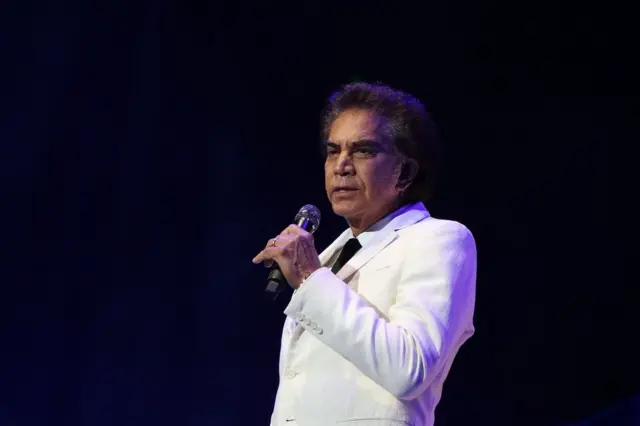 José Luis Rodríguez vestido de blanco con un micrófono en la mano