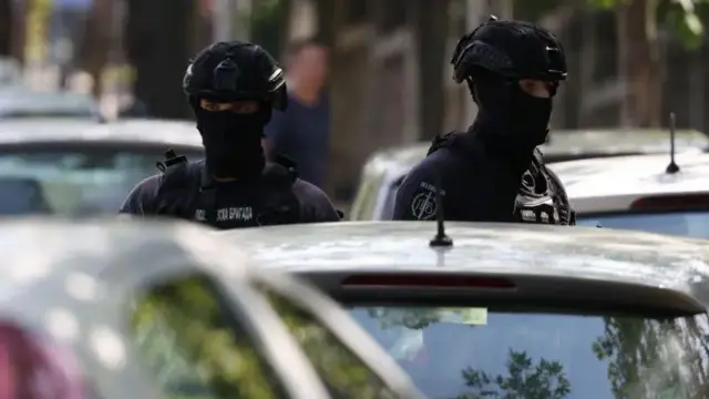 Dvojica policajaca u punoj opremi ispred automobila