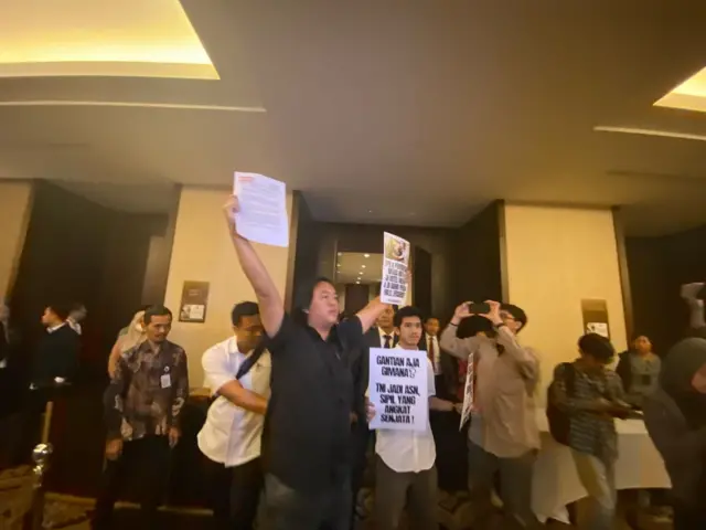 Andrie Yunus, yang juga merupakan Wakil Koordinator Komisi Untuk Orang Hilang dan Korban Tindak Kekerasan (KontraS), memprotes pembahasan tertutup Revisi UU TNI antara DPR dan pemerintah di sebuah hotel bintang lima di Senayan, Jakarta, pada Sabtu (15/03).