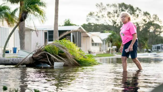 Una mujer que cambia por una zona inundada tras el paso de Milton.