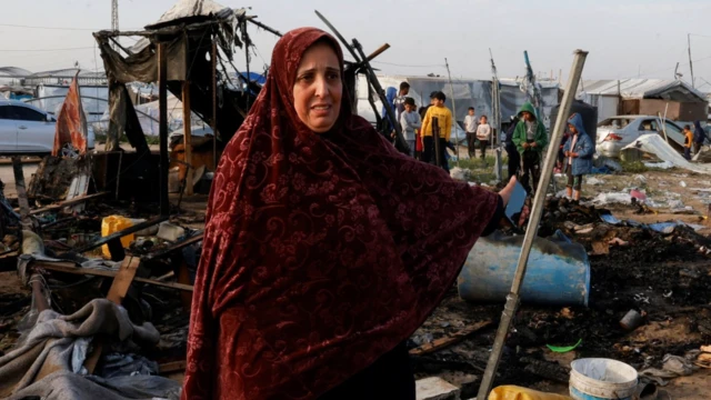 Seorang perempuan Palestina memberi isyarat saat orang-orang memeriksa lokasi serangan Israel terhadap kamp tenda yang menampung pengungsi, di daerah Al-Mawasi, di Khan Younis di Jalur Gaza selatan pada Selasa (18/03).