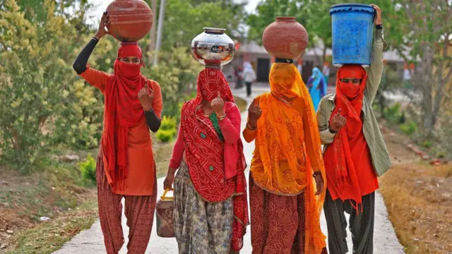 अप्रैल, 2024 में राजस्थान के दुदू में पानी लेकर आती महिलाएं अपनी उंगलियों पर लगी अमिट स्याही दिखाती हुईं. भारत में महिलाओं का मतदान प्रतिशत तो बढ़ा है लेकिन प्रतिनिधित्व अब भी कम है