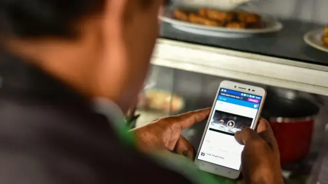 Seorang pria nampak membuka aplikasi Facebook pada telepon pintarnya saat jeda makan siang di Jakarta, pada 2 Marer 2018. 