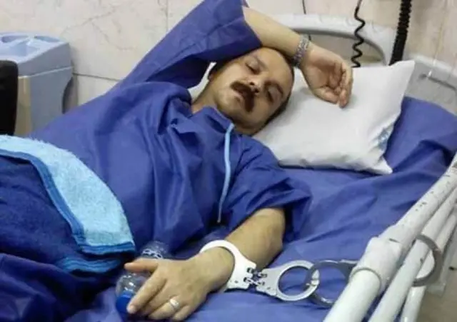 رضا شهابی در تخت بیمارستان درحالیکه به دستش دستبند زدند