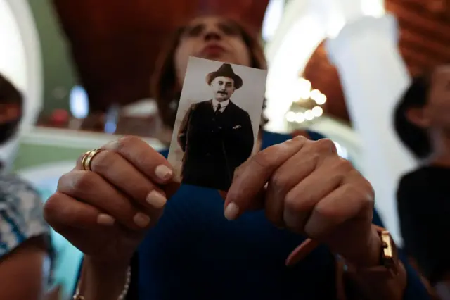 Una mujer sostiene una estampa de José Gregorio Hernández
