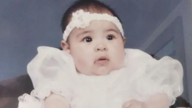  Lopez re ni kekere to wọ aṣọ funfun ati sikaafu.