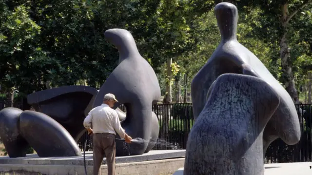 Tukang kebun menyirami rumput di depan patung Henry Moore di halaman Museum Seni Kontemporer Tehran, September 1993.