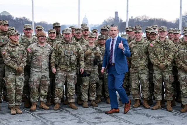 ABD Savaş Bakanı Pete Hegseth, Amerikan askerlerinin önünde poz veriyor