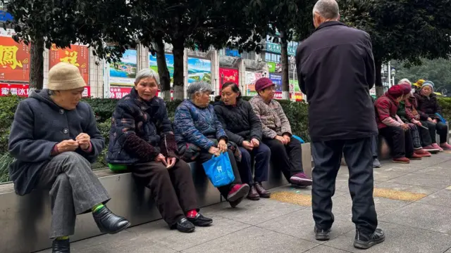 2025年3月，中国重庆，一群老人坐在城区的公共长椅上交谈