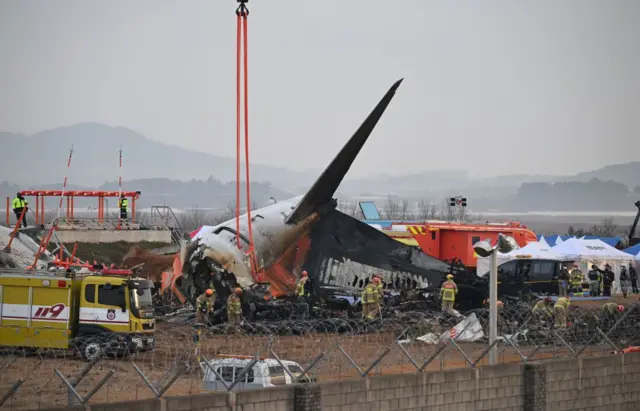 Petugas pemadam kebakaran bekerja di reruntuhan pesawat Jeju Air di Bandara Internasional Muan di Muan, Korea Selatan, pada 29 Desember 2024.