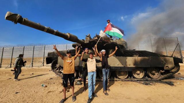 O braço armado do Hamas, as Brigadas Izz ad-Din al-Qassam, seguram uma bandeira palestina enquanto destroem um tanque das forças israelensesfifa na betGaza