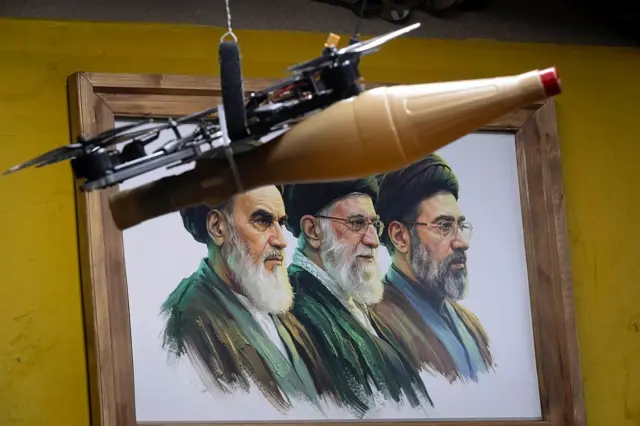 تصویر روحالله خمینی، علی خامنهای و مجتبی خامنهای در یک قاب و یک ریزپرنده مسلح در بالای قاب دیده میشود
