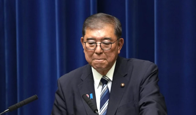 O primeiro-ministro Shigeru Ishiba, vestindo um terno cinza-escuro, camisa branca e gravata listrada de azul e branco, em um pódio com dois microfones, durante uma entrevista coletiva em Tóquio, 7 de setembro de 2025