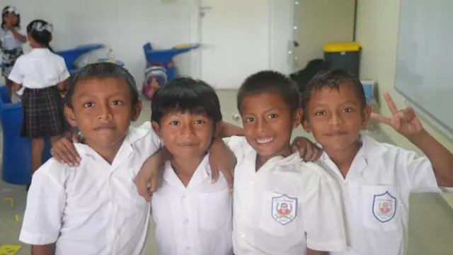 Quatro crianças posam em uma sala de aula no Centro Educacional Sahila Olonibigiña.