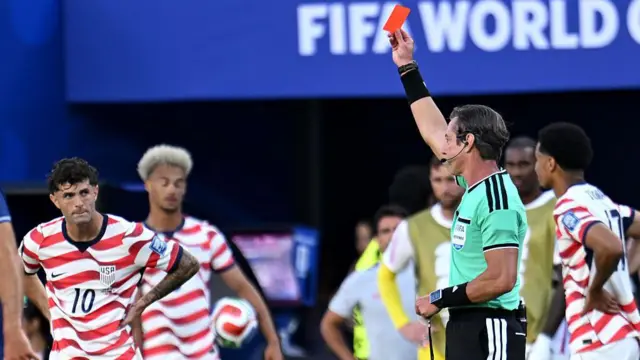 Claus apresentando um cartão vermelho ao jogador americano Balogun.