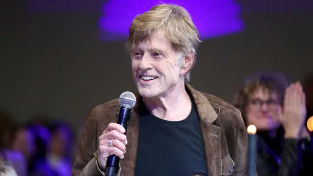 Robert Redford photographié à l'âge de 84 ans. Il parle dans un micro. 