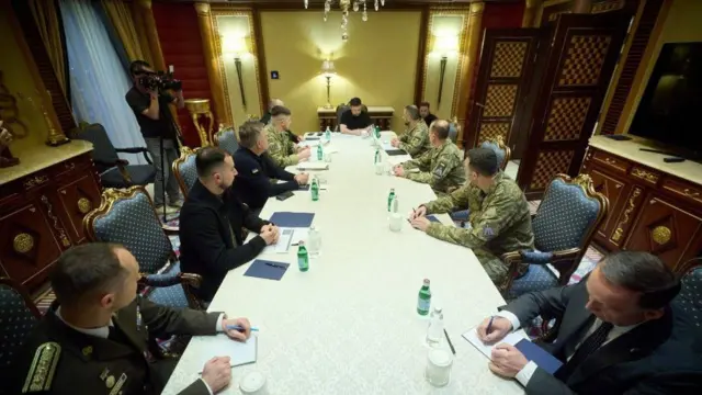 За столом сидять Зеленський (у центрі), ліворуч - члени делегації, яка поїхала з ним на Близький Схід у березні 2026 року, а праворуч - троє українських військових, які ділилися експертизою з арабськими країнами в питаннях збиття дронів. 