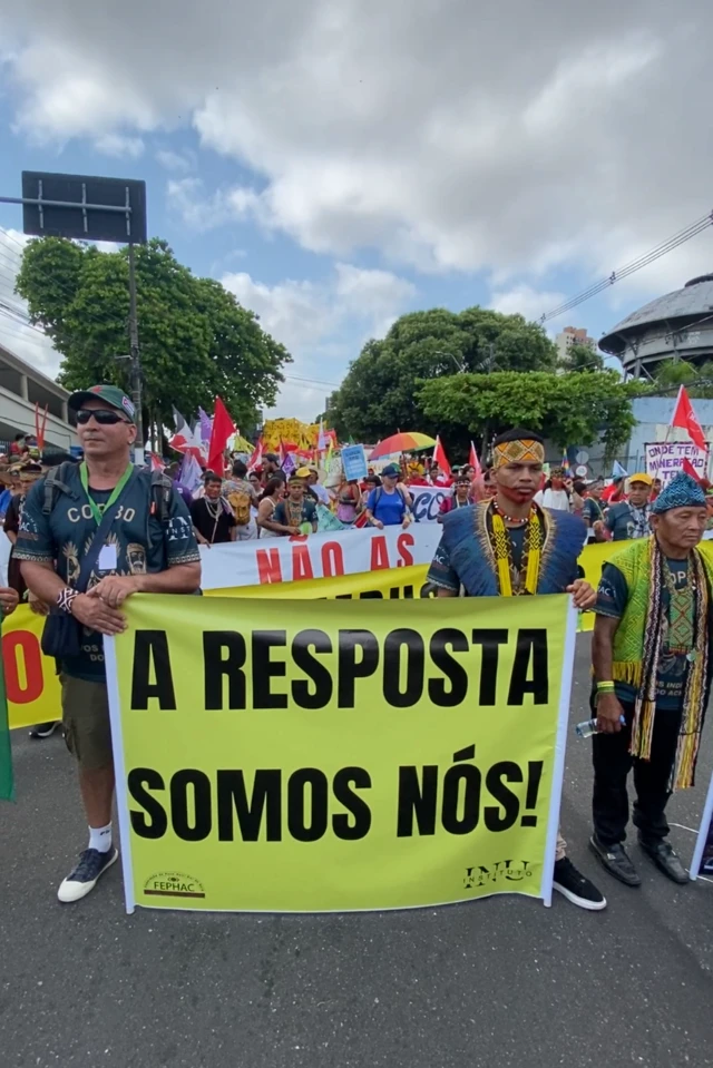 Manifestantes indígenas segurando um cartaz onde se lê "A resposta somos nós"