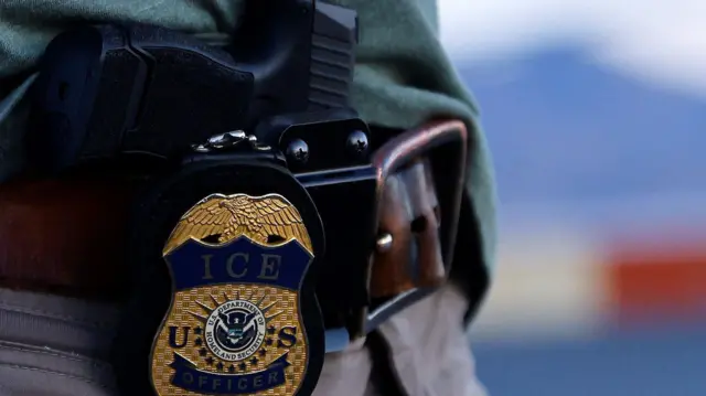 Pištolj i značka sa logom Službe za imigraciju i carinu (ICE)