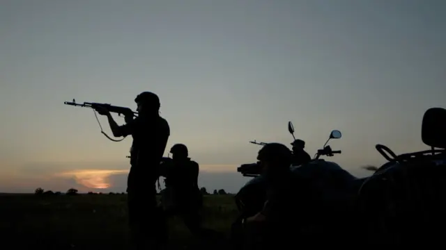 Силуэты военных с автоматами на фоне закатного неба