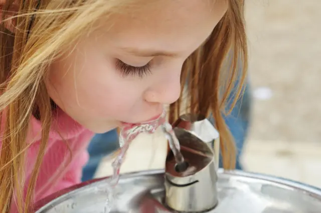 ታዳጊ ልጅ ውሃ እየጠጣች 