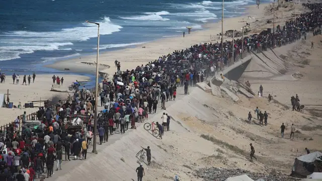 Дорога Аль-Рашид в секторе Газа, 10 октября 2025. Палестинцы идут по берегу моря: видна длинная вереница людей на песчаном пляже