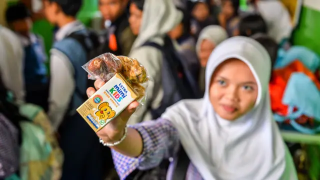 Siswi menunjukkan paket Makan Bergizi Gratis (MBG) saat dibagikan di SMP Kemah, Bandung, Jawa Barat, Selasa (24/2/2026).