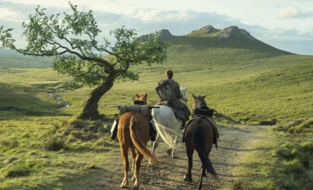 Üç atla birlikte ilerleyen bir erkeği görüyoruz. Oldukça güzel bir manzara içinde yem yeşil bir alanda ilerliyor.
