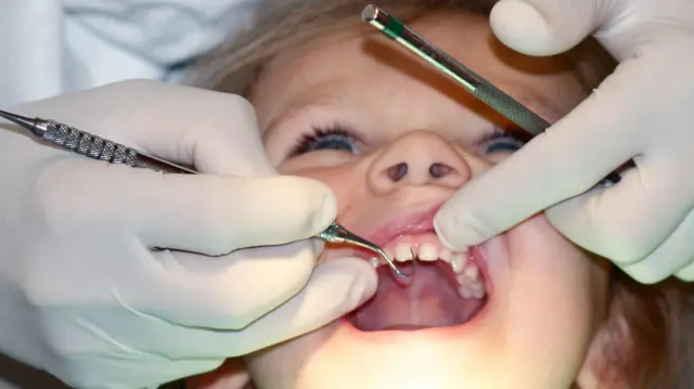 Una niña siendo vista por un dentista.