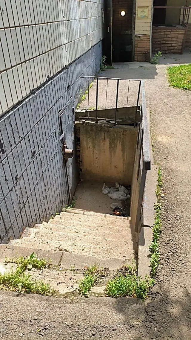 Замусоренная лестница в подвал многоквартирного дома.