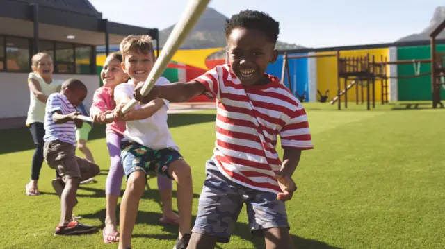 கயிறு இழுக்கும் போட்டியில் ஈடுபட்டுள்ள பல்வேறு இனங்களைச் சேர்ந்த பள்ளி மாணவர்கள்