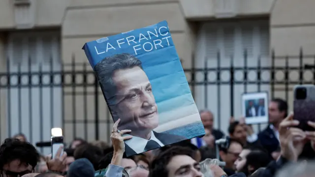Сторонник Саркози держит плакат с его портретом и надписью La France Fort.