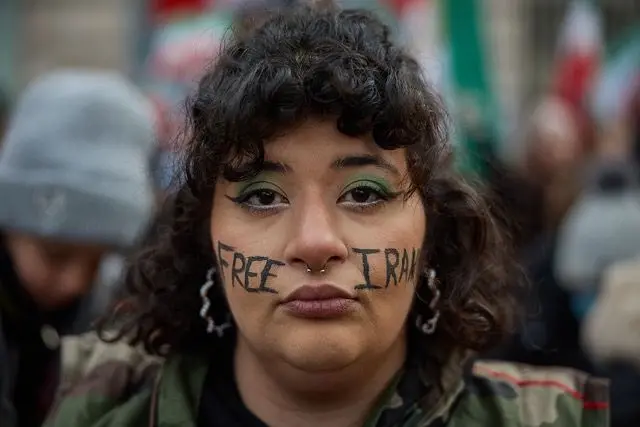 معترضی در تجمع پاریس که بر صورتش نوشته ایران آزاد