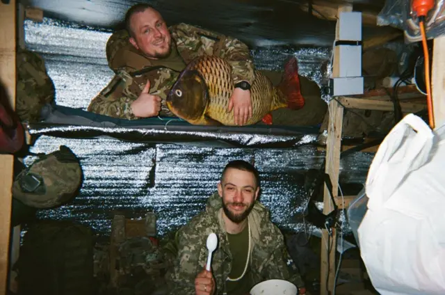 Двоє військових відпочивають, у одного подушка у вигляді великої риби 