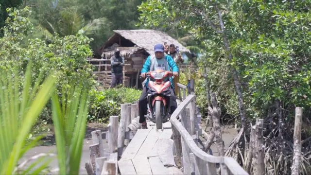 Dengan menggunakan sepeda motor, Abdi menerobos pasir hitam di bibir Pantai Pinus Moilong menuju sarang burung maleo.