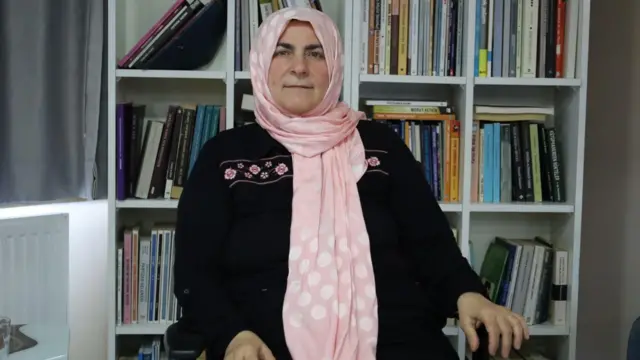 Fatma Bostan Ünsal bir sandalyede oturuyor ve kameraya bakıyor.