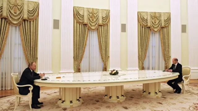 Vladímir Putin, en una gran mesa en el Kremlin. Al otro extremo, Olaf Scholz. 
