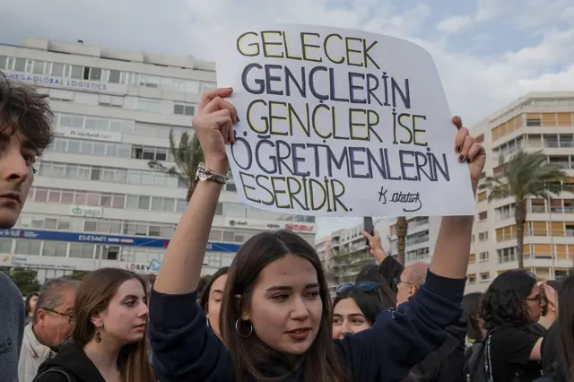 İzmir'de bir genç kadın öğrenci, elinde pankart ile protestolara katılıyor. 