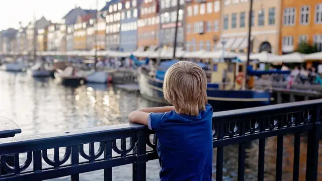 Dete naslonjeno na ogradu mosta posmatra reku koja protiče pod njim