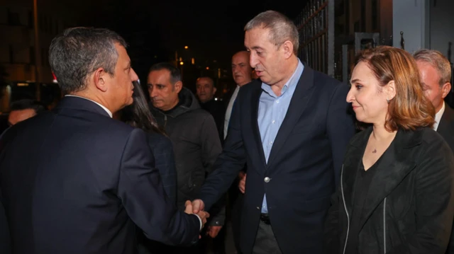 Özgür Özel, kravatsız Tuncer Bakırhan'ın elini sıkıyor sokakta ve karanlıkta. Yanda iki partiden isimler var.