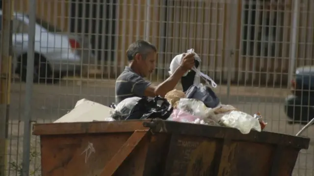 Un homme fait les poubelles
