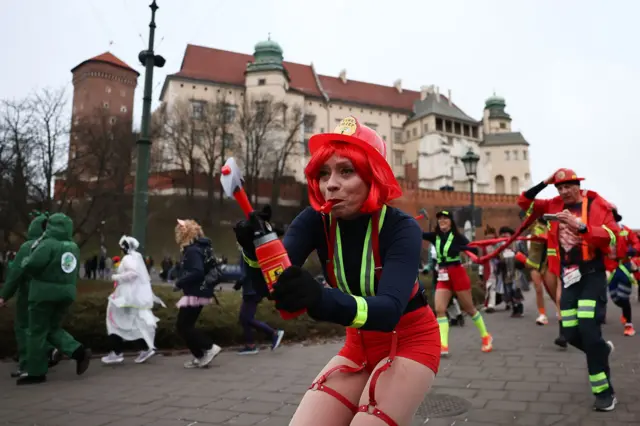 People dressed up in different costumes, including firemen and women, run in the New Year's Eve Run in Krakow, Poland